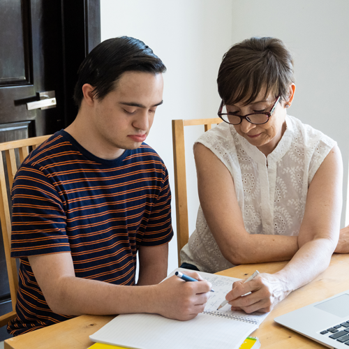 Mom helping young teenager son with online home schooling.
